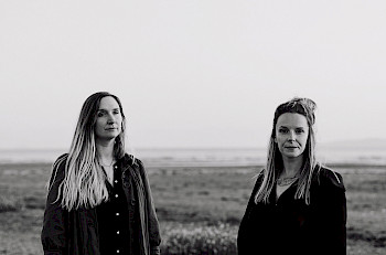 Schwarz-Weiß-Bild: Rachel Newton & Lauren MacColl vor einem Feld