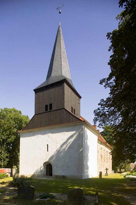weiße Kirche von schräg vorne, mit grauen Kirchturm