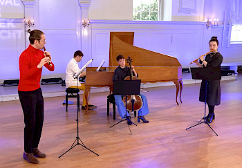 4 MusikerInnen spielen Musik in einem Raum